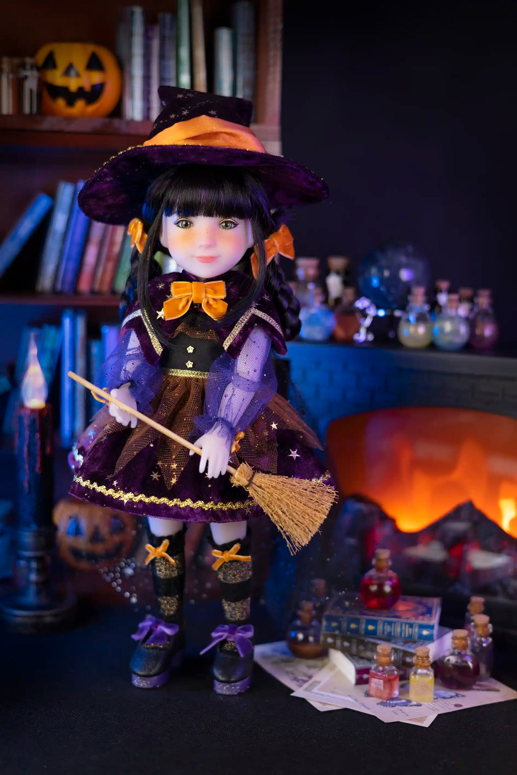 Halloween-themed doll in a witch costume with broom and pumpkins in the background