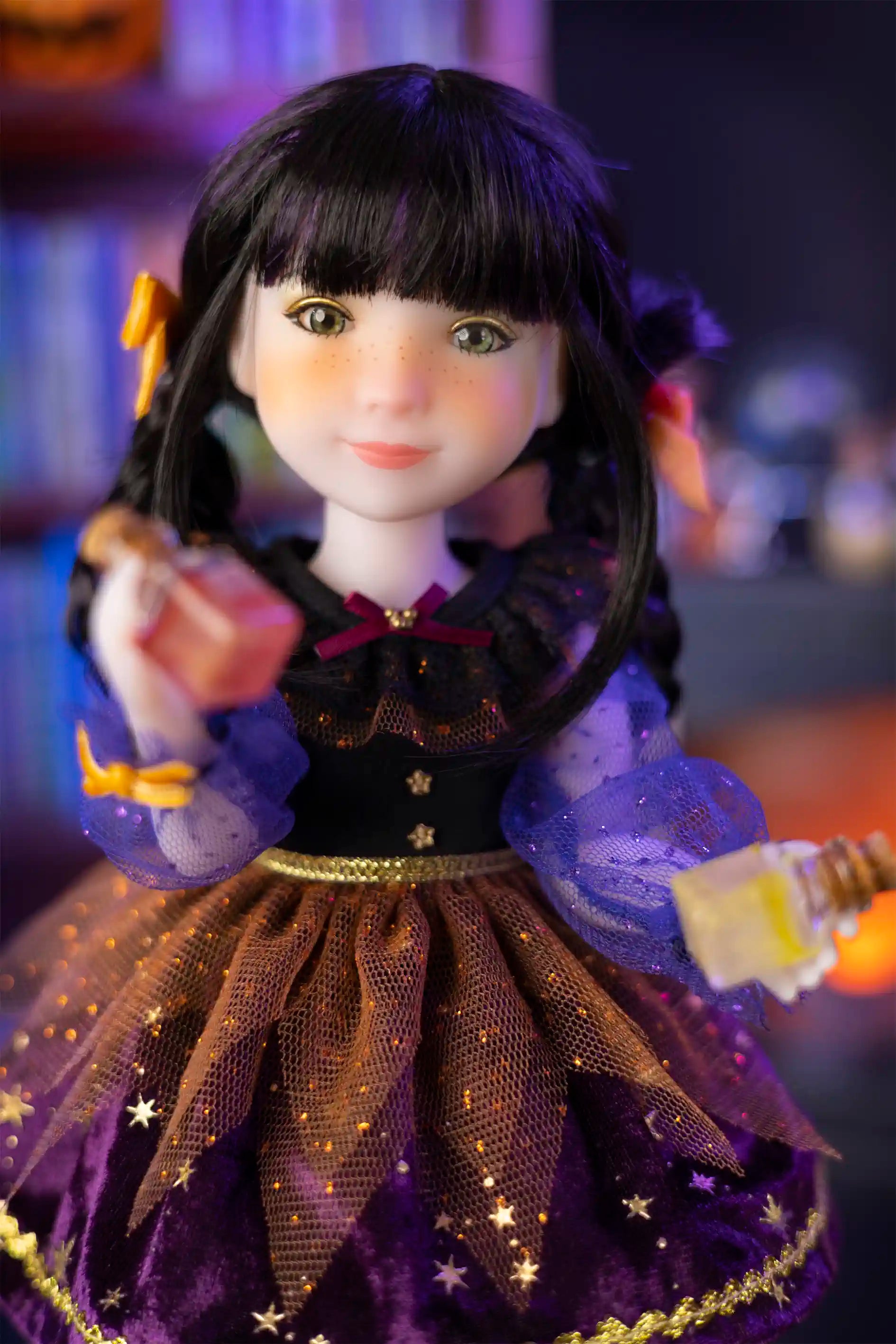 Doll with black hair styled in pigtails, wearing a black and purple outfit with gold accents.